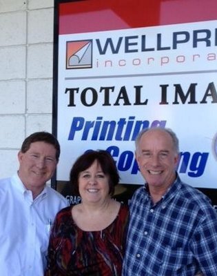 The Wellprint team in front of the Wellprint Incorporated / Total Image sign